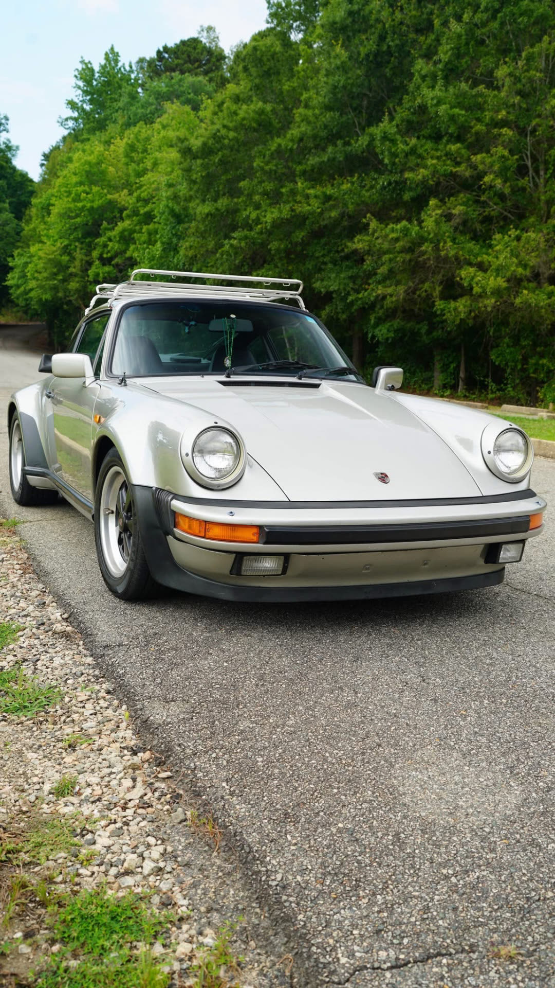 Silver Porsche 911 Turbo parked on a gravel drive lined with trees
