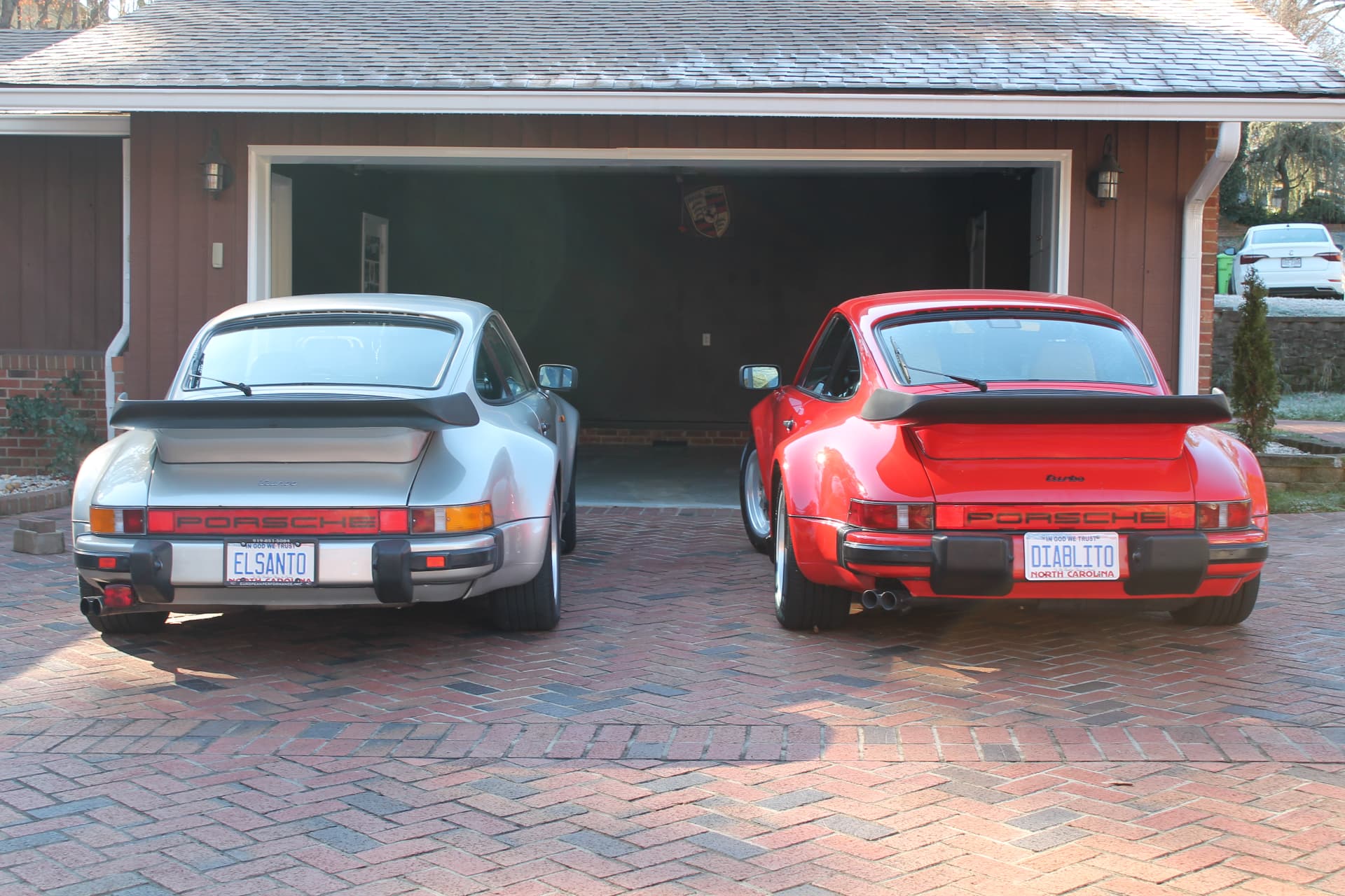 Silver Porsche 911 Turbo parked in the driveway of a modern white brick home