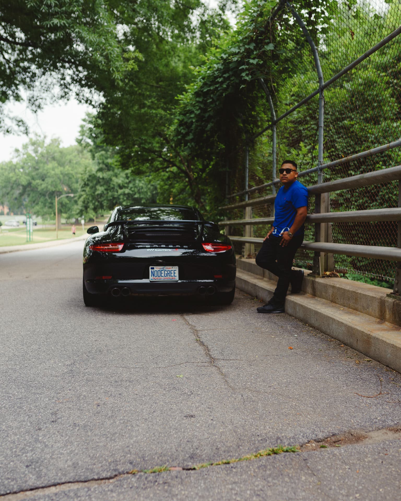 Black Porsche 911 Turbo parked on a bridge with a man standing beside it