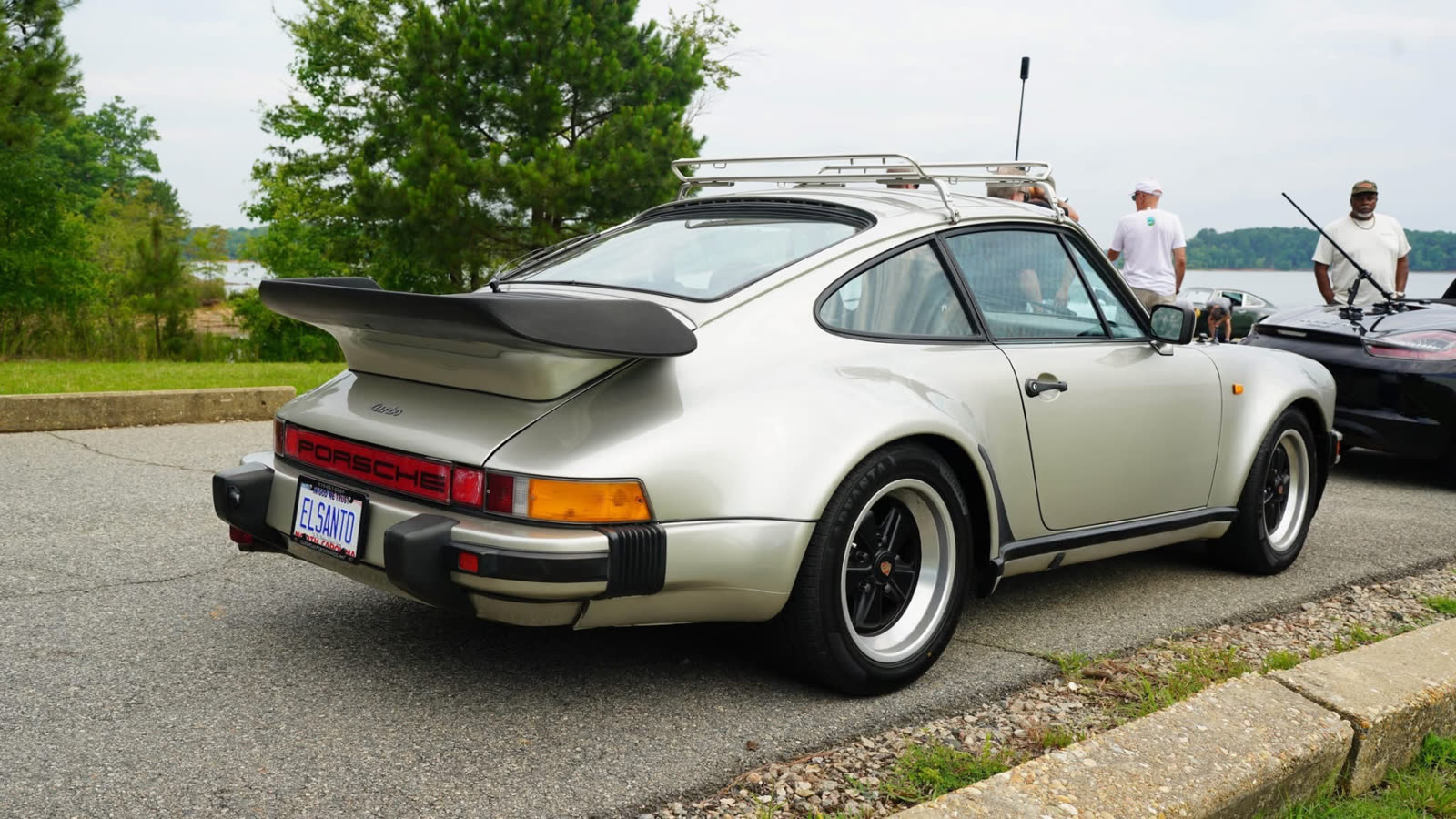 Rear three-quarter of a silver Porsche 911 Turbo at a waterfront car meet