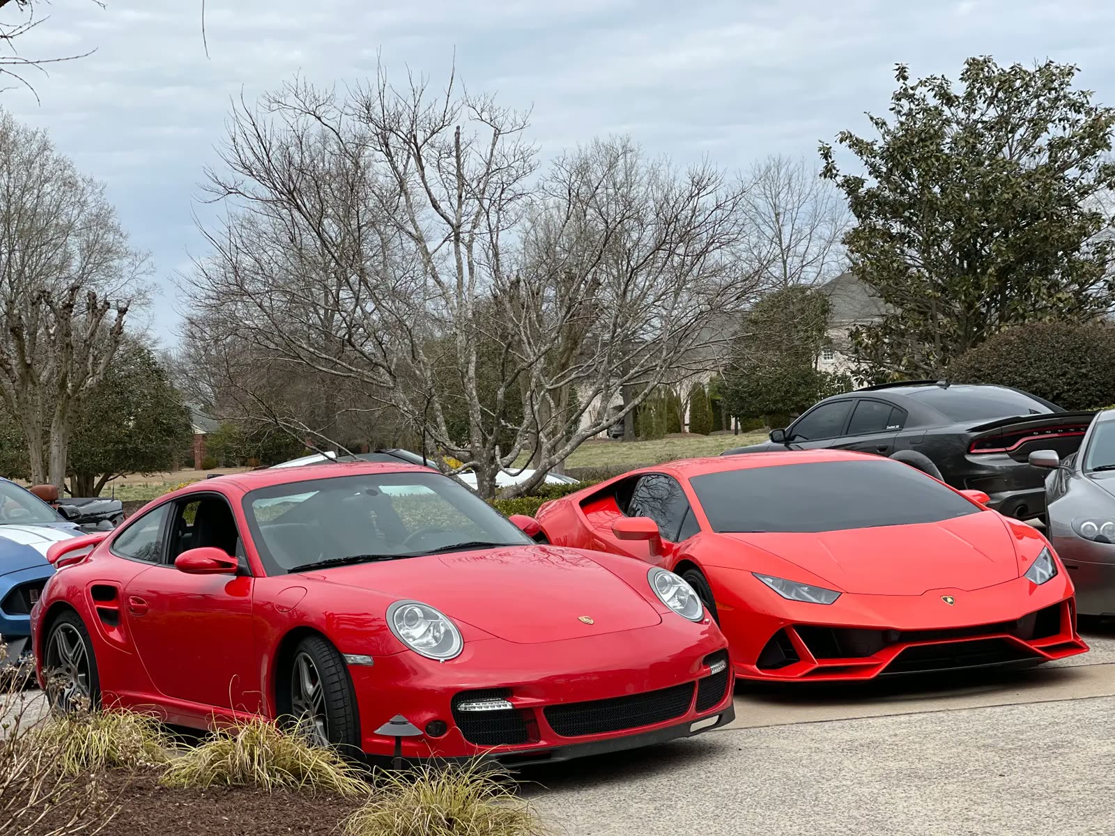 Red Porsche 911 Turbo parked beside a red Lamborghini Huracán at a cars and coffee